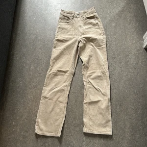 Beiga manchesterbyxor från Weekday - Snygga beiga manchesterbyxor från Weekday i rak modell. Byxorna har klassiska fickor fram och bak, samt bälteshällor i midjan. Perfekta för dig som gillar en avslappnad och stilren look.