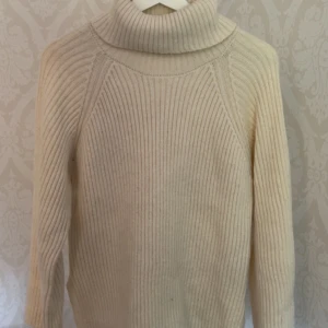 Beige polotröja från Gina Tricot - Ribbstickad beige polotröja från Gina Tricot i storlek XS. Tröjan har hög polokrage och långa ärmar, perfekt för lager på lager. Mjuk och skön känsla med klassisk passform som funkar till många olika stilar.