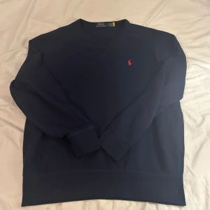 Mörkblå sweatshirt Polo Ralph Lauren - Klassisk mörkblå sweatshirt från Polo Ralph Lauren med röd broderad logga på bröstet. Tröjan har rund halsringning, långa ärmar och är gjord i mjuk bomullsfleece. Perfekt för en chill och stilren look. Köpt från boozt förra julen✌️