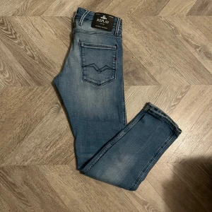 Replay Anbass ljusblå jeans - Snygga Replay Anbass jeans i ljusblå tvätt med klassisk femficksdesign och diskreta slitningar. Jeansen har smal passform, normal midja och är tillverkade i mjukt stretchigt denim för extra komfort. Perfekta för dig som gillar en modern och stilren look. Storlek 29 Weist och 30 length.