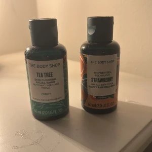 The Body Shop Tea Tree & Strawberry duo - Två små flaskor från The Body Shop: en Tea Tree Skin Clearing Facial Wash (grön, 60 ml) och en Strawberry Shower Gel (orange/röd, 60 ml). Båda är i plastflaska med skruvkork, perfekt för resan eller gymväskan. Tea Tree är för ansiktet och Strawberry är en söt, fruktig duschgel.