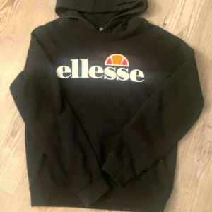 Svart Ellesse hoodie - Svart hoodie från Ellesse. Klassisk huva. Mjuk och skön, passar till allt. Använd fåtal gånger ser helt oanvänd ut.