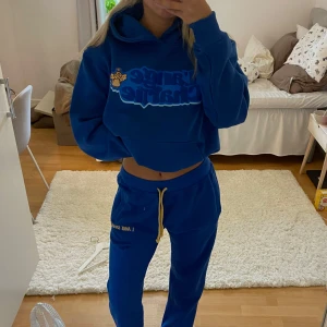 Mjukis Sett L'Ange Charlie med tryck - Mjukis Sett från L'Ange Charlie med coolt tryck framtill och en liten ängel. Tröjan har huva, magficka och ribbade muddar. Oversized och skön passform, perfekt för chill dagar. Materialet är mjuk bomull och polyesterblandning.