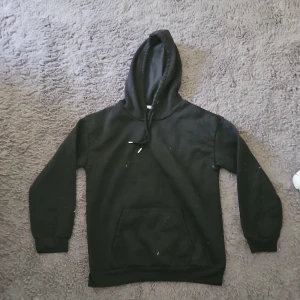 Svart hoodie med körsbärstryck bak - Svart hoodie med huva och magficka. På ryggen finns ett stort tryck av två rosa körsbär i discokulestil. Tröjan har långa ärmar och ribbade muddar. Perfekt för dig som gillar unika detaljer och vill sticka ut lite extra.