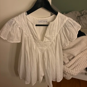 Vit blus från Lefties med v-ringning - Luftig vit blus från Lefties i storlek M. Blusen har v-ringning, korta puffärmar och ett lätt rynkat tyg som ger en avslappnad och bohemisk känsla. Perfekt till jeans eller kjol för en fräsch look. Super skön tröja då det passar till middag eller något finare. Säljer denna då den inte kommer till användning den är liten i storleken så skulle säga att den passar mer som Xs-S💕