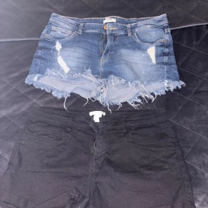 Två par jeansshorts från H&M - Säljer två par snygga shorts från H&M i storlek 38. Ett par är klassiska blå jeansshorts med slitningar och fransig kant, det andra paret är svarta jeansshorts med enkel design. Båda har femficksmodell och dragkedja.