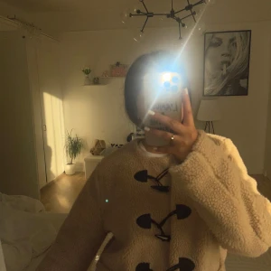 Beige teddyjacka från ONLY med knäppning - Supermysig beige teddyjacka från ONLY med svarta detaljer och snygga knäppningar framtill. Jackan har två fickor och är fodrad med ljusrosa tyg. Perfekt för kalla dagar och ger en chill vibe till din outfit.
