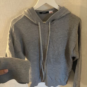 Grå stickad hoodie från Gina Tricot - Mysig grå hoodie från Gina Tricot i stickat material. Tröjan har huva, snörning framtill och ribbade muddar vid ärmslut och nederkant. Perfekt för dig som gillar en enkel och stilren look med lite oversized känsla. Jätte skön. Storlek xs men passar S också den e lite oversized. Nypris 500kr använd ca 2 ggr
