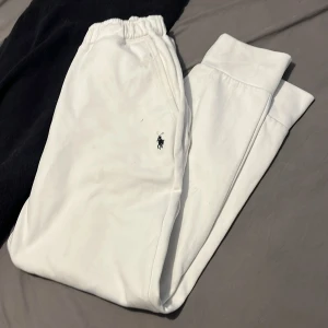 Polo Ralph Lauren mjukis - Snygga vita mjukisbyxor från Polo Ralph Lauren med klassisk broderad logga på benet. Byxorna har resår i midjan och muddar vid bensluten för en skön och avslappnad passform. Perfekta för chill dagar eller när du vill vara bekväm men ändå se fräsch ut. Ser lite smutsiga ut men tvättar allt noggrant innan frakt såklart! Snören borta, passar perfekt på mig 180cm lång.