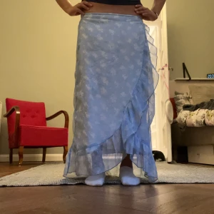 Blommig ljusblå kjol med volang - Säljer ett jättefin blommig ljusblå volangkjol som är använd för länge sen! Den har några slitningar och hål men de syns inte när man har på sig den. Den har också en fläck som inte helelr syns så mycket när man väl har på sig den