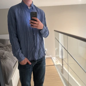 Blå linneskjorta Massimo Dutti - Snygg blå skjorta från Massimo Dutti i 100% linne. Skjortan har ett diskret paisleymönster i vitt, klassisk krage med knappar och lång ärm. Perfekt för dig som gillar en avslappnad men stilren look. Storlek Xl passar L och M. Jag är 185cm och väger 75kg🔥