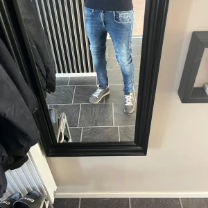 Replay Anbass slim fit jeans blå 31W/30 L - Säljer ett par Replay Anbass slim fit jeans i klassisk blå tvätt med snygga slitningar och kontrastsömmar. Jeansen har fem fickor, dragkedjegylf och är tillverkade i stretchig bomullsdenim för en bekväm passform.