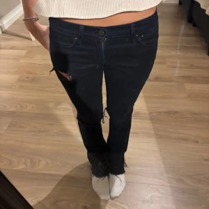 Svarta slitna bootcut jeans - Säljer ett par svarta jeans med bootcut-modell och snygga slitningar vid knäna och låret. Passar mig som är 160 cm