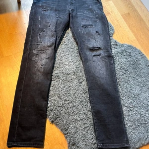  jeans Jack & Jones 33/32 - Svarta jeans från Jack & Jones i storlek 33/32. Modellen har skinny passform och slitna detaljer framtill för en cool, trendig look. Klassisk femficksdesign och stretchigt bomullsmaterial som sitter skönt hela dagen.