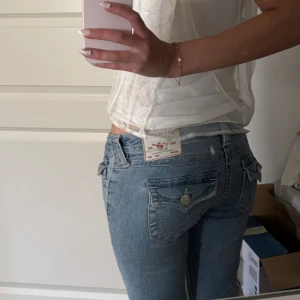 True Religion Joey Low Rise Flare Jeans - Säljer ett par ljusblå True Religion Joey jeans med låg midja och flare-ben. Klassiska detaljer med stora ficklock bak och snygga sömmar. Jeansen är i bomull och har en ikonisk True Religion-patch bak. Säljer eftersom de är för korta för mig som är 175cm. Fråga om du vill ha mera bilder eller mått ❤️