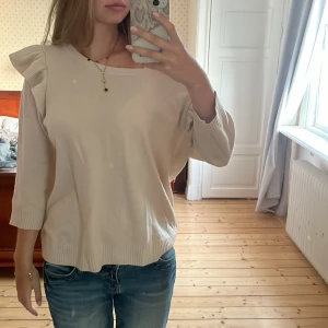 Beige stickad tröja med volang H&M XL - Säljer en beige stickad tröja från H&M i storlek XL. Tröjan har trekvartsärmar och snygga volangdetaljer på axlarna. Den är ribbad vid ärmslut och nederkant, vilket ger en schysst passform. Perfekt för dig som gillar en enkel men ändå trendig look.