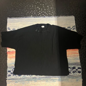 Svart ribbad tröja från Stockh LM Studio - Svart ribbad tröja från Stockh LM Studio i storlek M. Tröjan har en loose passform med breda ärmar och rund halsringning. Materialet är mjukt och stickat, perfekt för dig som gillar enkel och stilren design. Passar dig som vill ha en chill och oversized look.