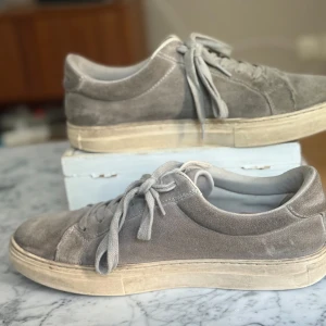 Grå mockasneakers från Vagabond - Snygga grå sneakers från Vagabond storlek 41 i mjuk mocka med klassisk rund tå och platt sula. Skorna är ganska använda vilket gör priset mindre men de är absolut användbara. 