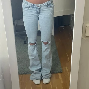 Ljusblå bootcut jeans med hål - Supersnygga lågmidjade bootcut jeans från Nelly med hål. De är ljusblåa och har rosa detaljer på fickorna. Inga defekter vad jag vet och superbra skick. Strl 34. Stretchiga och supersköna!