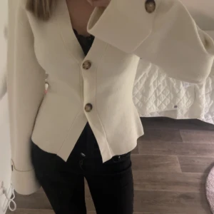 Beige kofta med stora knappar - Snygg beige kofta med markerad midja och stora dekorativa knappar framtill och på ärmsluten. Koftan har långärmad design och är tillverkad i ett mjukt material som känns lyxigt. Perfekt till hösten. Aldrig använd🤍