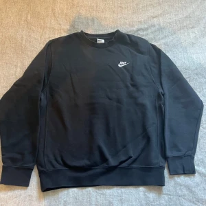 Svart sweatshirt från Nike - Svart crewneck sweatshirt från Nike med klassisk logga i vitt på bröstet. Perfekt för chill dagar eller när du vill ha en clean streetstyle-look. Vid snabb affär så kan priset diskuteras!