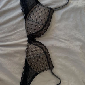Svart prickig spets-bh 70B intimissimi  - Säljer en svart push up bh från intimissimi med tunna axelband och fina spetsdetaljer. Kuporna är dekorerade med små svarta prickar i mesh och har spets längs kanterna. Baksidan är slät och enkel. Använd enbart en gång då jag tagit bort prislapparna innan ja provade och sedan va den för liten. Köpte för 549 kr