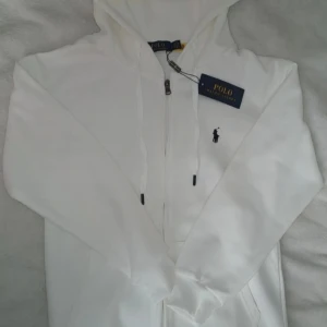 Ralph Lauren Zip Up - Ralph Lauren zip-up, vit – helt ny! Snygg och klassisk vit zip-up från Ralph Lauren i storlek S. Helt ny med prislapp kvar. Nypris högre – säljer för 699 kr, men pris kan diskuteras. Väldigt fin och perfekt till höstgarderoben!
