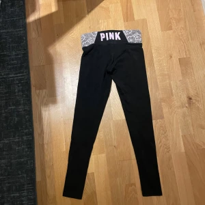 Vicitoria secret tajts - Svarta leggings från PINK Victoria's Secret med Rosa blommigt mönster upptill. Stretchigt material i bomull och elastan, perfekt för yoga eller chill. Snygg rosa PINK-logga på midjan. Superskön passform och stilren look. Har en del slitage (ihopsydda) fråga för mer bilder.