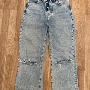 Ljusblå jeans med slitningar  - Ljusblå jeans med raka ben och snygga slitningar över knäna från Bikbok. Endast använda fåtal gånger pga. för små på mig. Passar bra i längd på mig som är 180. Nypris 599