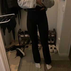 Svarta bootcut byxor med hög midja, kostymbyxor  - Säljer ett par svarta byxor med hög midja och bootcut-modell. De sitter tight över låren och släpper ut nedtill för en snygg siluett. Perfekta att styla med sneakers eller chunky boots. Materialet är stretchigt och bekvämt.
