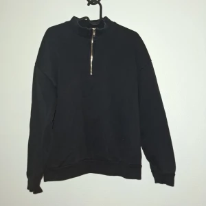 Svart oversized tröja från FSBN - Svart oversized sweatshirt från FSBN i storlek XS. Tröjan har en hög krage och en snygg half zip-dragkedja framtill. Tillverkad i mjuk bomullsmix och har långa ärmar med ribbade muddar. Perfekt för en chill och avslappnad stil.