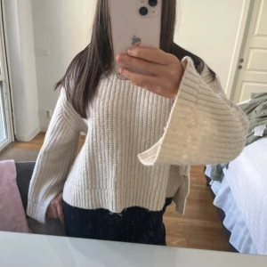 Beige stickad tröja med vida ärmar - Säljer en beige stickad tröja med breda, långa ärmar och ribbad struktur. Tröjan har en loose passform och är perfekt för dig som gillar en chill och comfy stil. Rund hals och slitsar i sidorna ger extra vibe. 