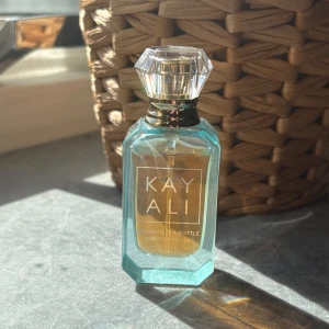 Kayali Maldives In A Bottle parfym - Snygg parfymflaska från Kayali, modellen Maldives In A Bottle Ylang Coco 20. Flaskan är turkos med en transparent, multifacetterad kork i plast och guldiga detaljer. Doften har tropiska och blommiga inslag, perfekt för dig som gillar exotiska vibbar. Flaskan rymmer 10ml. Se bild att lite använts. 