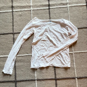 Vit långärmad topp från Brandy Melville - Vit långärmad topp från Brandy Melville i mjuk bomull. Enkel och clean design med rund halsringning och smal passform. Perfekt att styla med jeans eller kjol för en chill look.