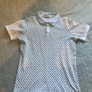 Burberry pikétröja - Vit pikétröja från Burberry med svart prickigt mönster över hela tröjan. Säljer för att den passar inte mig längre tyvärr. Vid snabb affär kan man få tröjan för ett billigare pris!