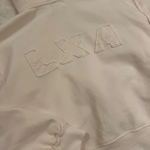LXA Hoodie - Jättesnygg beige hoodie ifrån LXA med fina detaljer, bara använt den 1 gång. Storlek xxs, jag brukar ha xs eller s i vanliga fall.