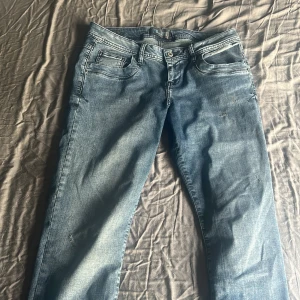 Blå bootcut jeans från LTB - Snygga blå jeans från LTB med bootcut-modell och låg midja. Jeansen har klassisk femficksdesign, ljus tvätt och subtila slitningar. Perfekta för dig som gillar en avslappnad och trendig look. Materialet är mjukt denim som sitter skönt hela dagen. Säljer pågrund av förstora på mig. endast använda få gånger 