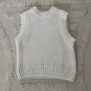 Vit stickad väst från H&M - Säljer en stickad väst i vitt från H&M i storlek XS. Västen har grovstickad struktur, ribbade kanter vid hals, ärmhål och nederkant.
