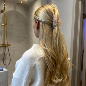 Rosa hårklämma med pärldetaljer - Säljer en elegant beige melerad hårklämma med pärldetaljer i guld. Perfekt för att sätta upp håret med stil. Klämman har en skimrande yta som ger en lyxig känsla. Oanvänd, endast testad för bilden!