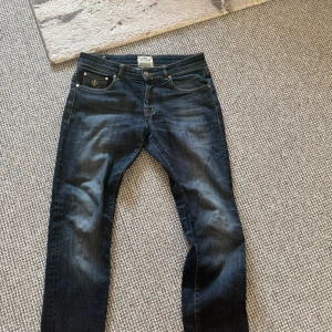 Mörkblå jeans från Morris - Snygga mörkblå jeans från Morris med klassisk femficksdesign och knappgylf. Jeansen har en lätt tvättad look och är perfekta för en stilren vardagsoutfit.