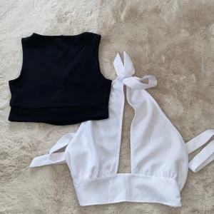 Svart och vit topp - Två snygga toppar, en svart ärmlös och en vit med knytning fram. Perfekta för sommardagar eller en utekväll. För endast 80 sek!💗.