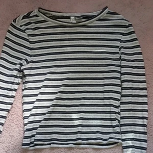 Randig långärmad tröja från H&M - Säljer en randig långärmad tröja från H&M i svart och vit. Tröjan har en normal passform och är perfekt för både höst och vår. Den är tillverkad i ett mjukt och bekvämt material.