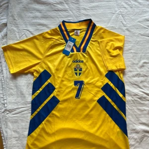 Henrik Larsson - Sveriges hemma tröja från VM 1994 med Ikonen Henrik Larsson på ryggen.                                                             Tröjan är helt ny och storlek M