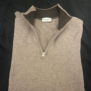 Beige tröja med dragkedja från John Henric - Säljer en stilren beige tröja från John Henric med dragkedja vid halsen. Perfekt för kyligare dagar med sin långärmade design. Tröjan har en enkel och klassisk look som passar till många tillfällen. Tröjan är använd fåtal gånger och har inga defekter