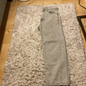 Grå baggy jeans från Pull&Bear - Säljer ett par grå baggy jeans från Pull&Bear. De har en avslappnad passform och är perfekta för en casual look. Jeansen har en klassisk design med fem fickor och bälteshällor.