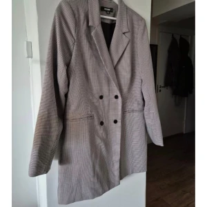 Missguided Kavajklänning  - Kavajklänning med dubbelknäppning och klassisk krage. Kavajen har en stilren design med två knappar framtill och långa ärmar. Perfekt för en chic look.