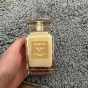 Tom Ford Vanilla Sex Eau de Parfum - Elegant parfymflaska från Tom Ford med doften Vanilla Sex. Flaskan är genomskinlig med en gyllene etikett och innehåller 100 ml Eau de Parfum. Perfekt för den som älskar en lyxig och sensuell vaniljdoft.
