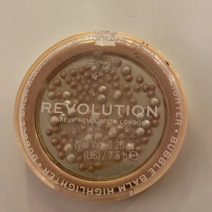 Highlighter från Makeup Revolution - Highlighter i form av pärlor från Makeup Revolution London. Produkten kommer i en rund, transparent förpackning med en mix av skimrande pärlor i olika nyanser av guld och silver. Perfekt för att ge ansiktet en strålande lyster.