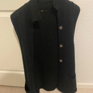 Svart stickad väst från Time - Snygg svart stickad väst från Time med knappar framtill. Perfekt för lager-på-lager-stil och ger en mysig känsla. Passar bra till både vardag och mer uppklädda tillfällen.