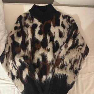Leopardmönstrad tröja från NA-KD - Säljer en snygg leopardmönstrad tröja från NA-KD i storlek S. Tröjan har en hög krage och är långärmad, perfekt för kyligare dagar. Den är gjord i ett mjukt material som känns skönt mot huden. 🐆